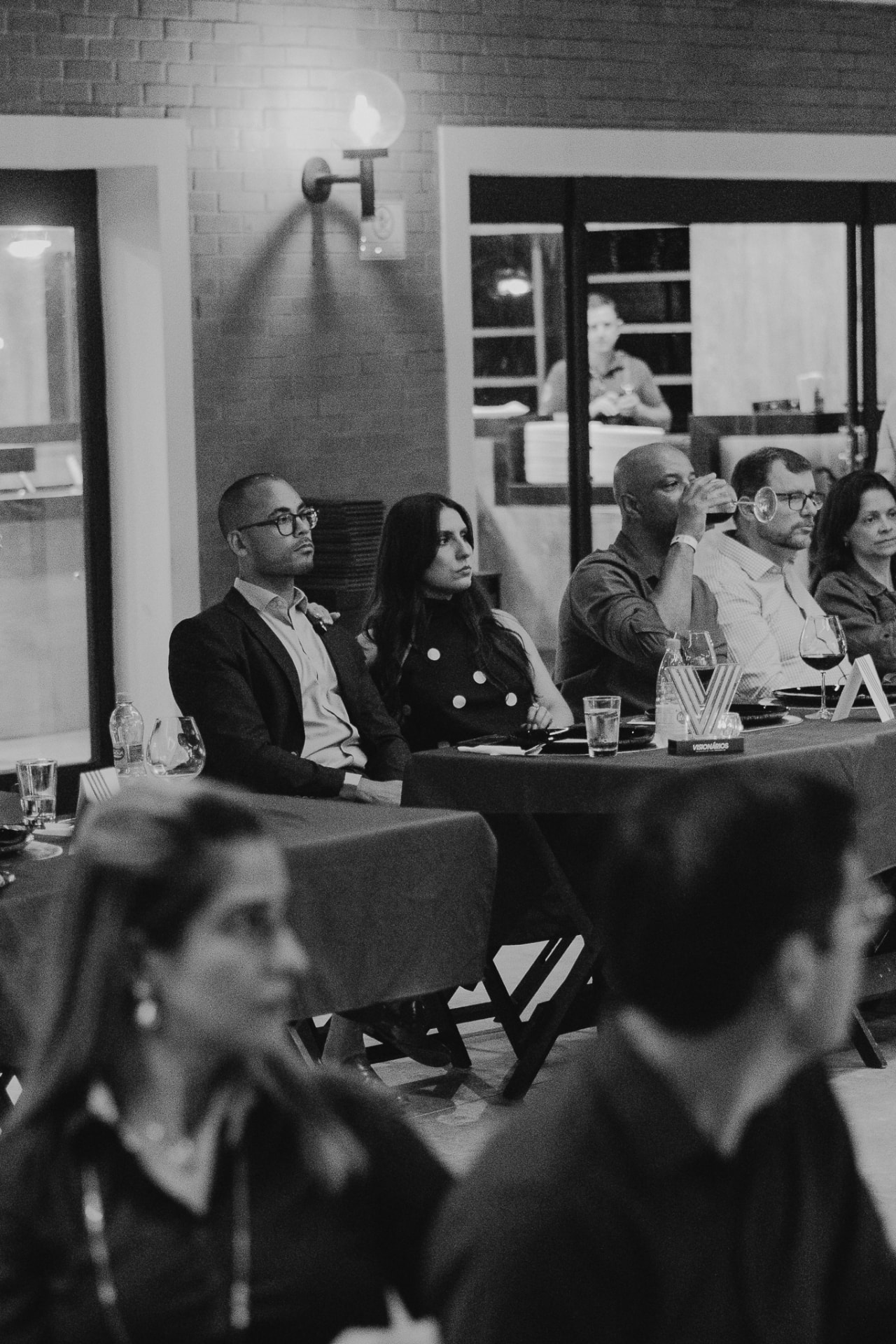 Participantes sentados às longas mesas acompanhando um encontro do Prime Club