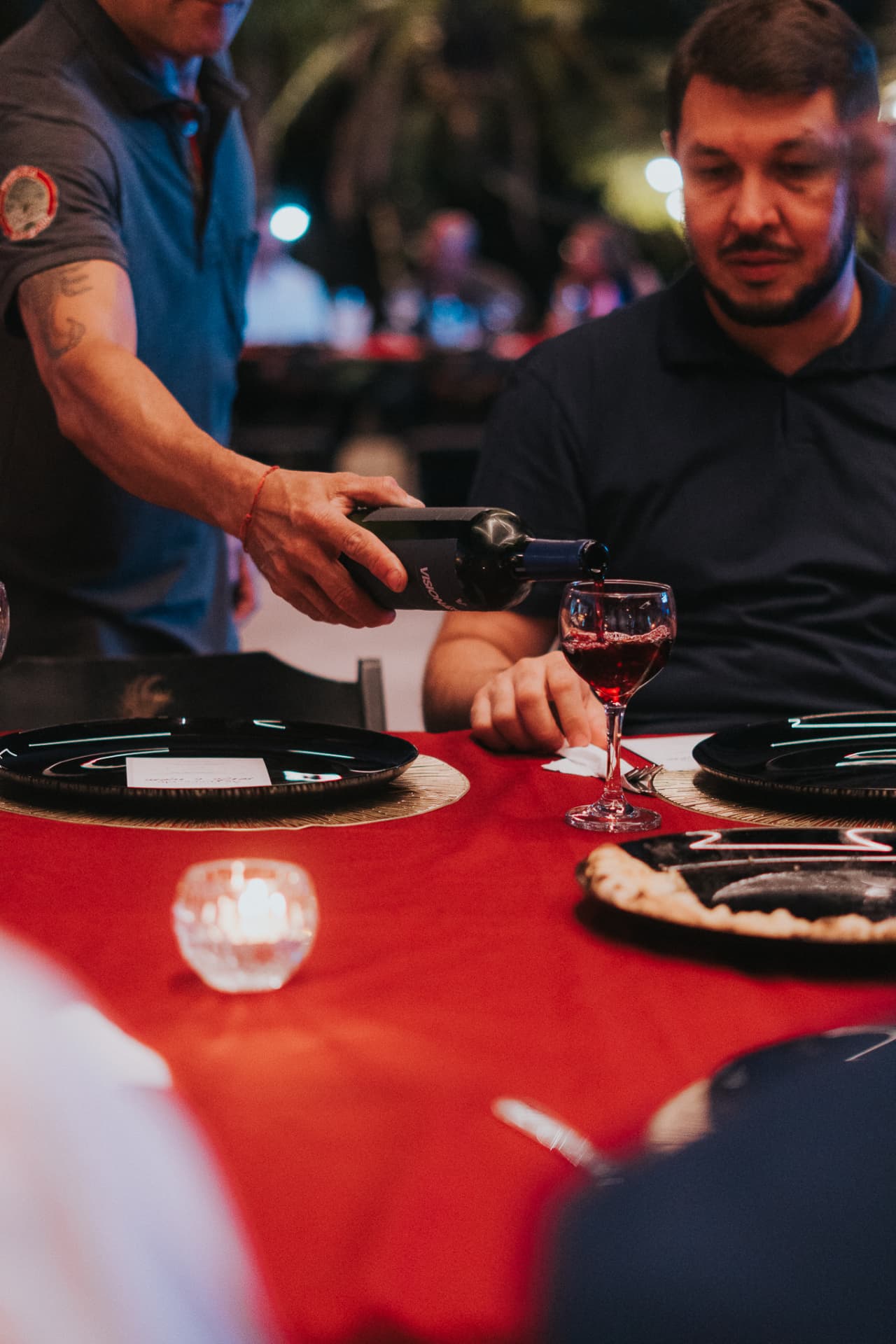 Garçom servindo vinho em uma mesa ao ar livre durante um jantar do Prime Club