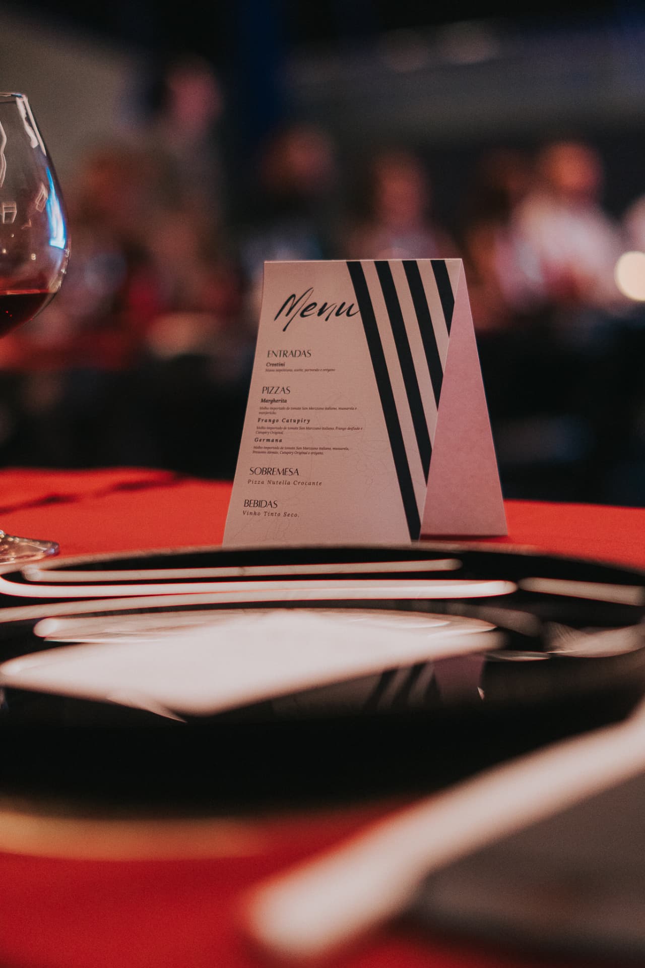 Cardápio do encontro sobre a mesa, ao lado de taça e prato