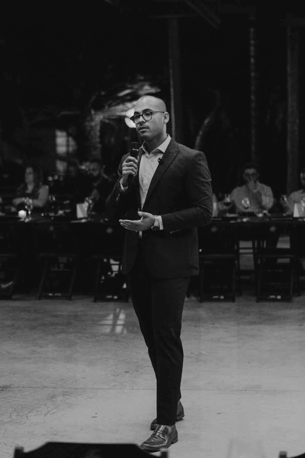 Empresário apresentando ao microfone diante dos convidados de um jantar do Prime Club